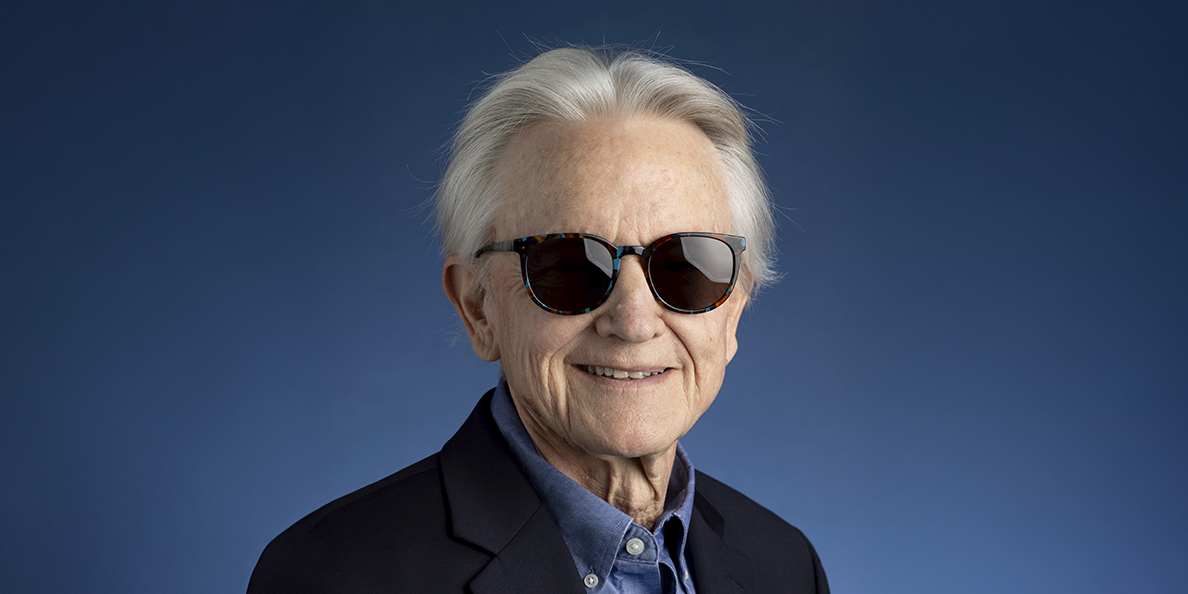 An older gentleman posing for a portrait with sunglasses on.